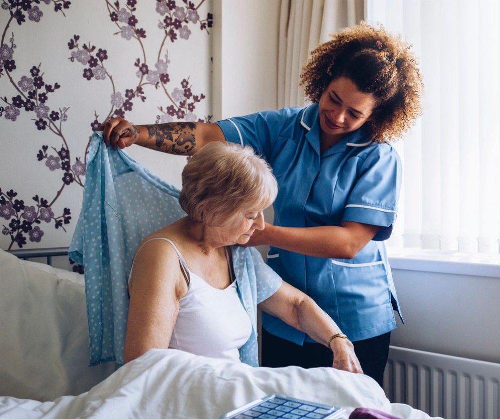 A woman helping an older person in bed